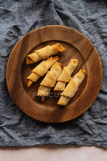 Dall'alto cornetto appetitoso croccante saporito in piatto di legno su tela di lino su tavolo — Foto stock