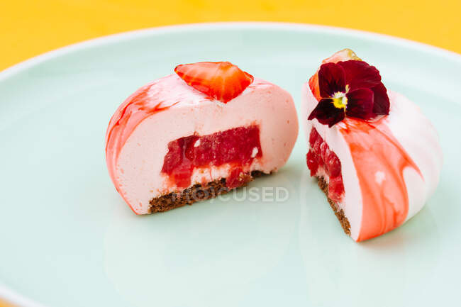 Closeup halves of delicious strawberry pastry with jam filling decorated with flower and placed on plate — Stock Photo