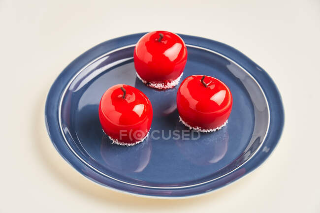 Pastel en forma de manzana de arriba con glaseado rojo colocado en el plato sobre fondo blanco - foto de stock