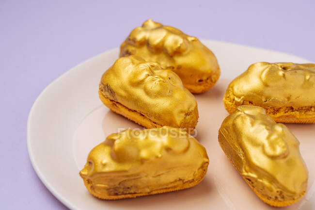 Tasty eclairs with golden icing — Stock Photo
