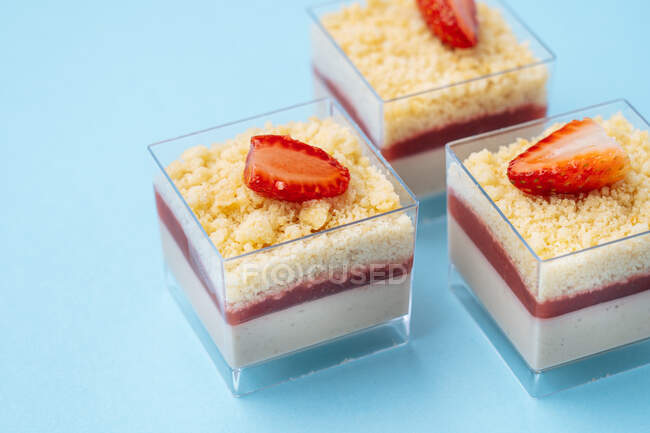 Closeup square glass cups with delicious strawberry mousse placed on blue background — Stock Photo