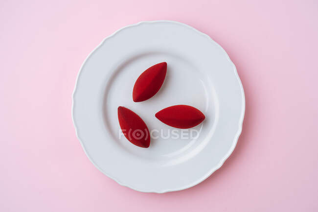 Biscotti gustosi sopraelevati con glassa rossa disposti su piatto di porcellana su fondo rosa — Foto stock