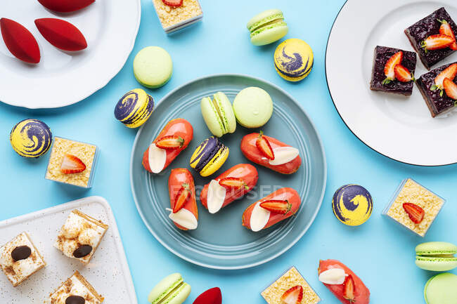 Vista dall'alto di biscotti e torte assortiti posizionati su piatti su sfondo blu — Foto stock