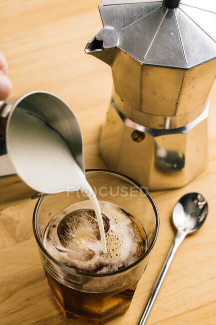 Unrecognizable barista filling glass of coffee with milk — Stock Photo