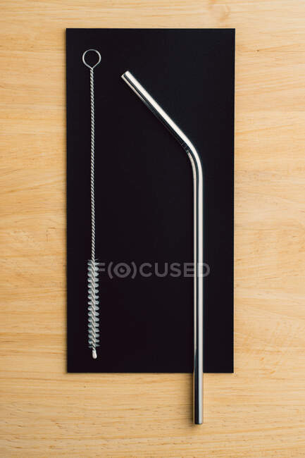 Top view of reusable metal straws and cleaning brush in row on wooden table — Stock Photo