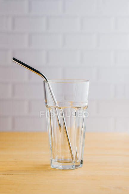 Paille durable en acier brillant écologique en verre vide sur table en bois — Photo de stock
