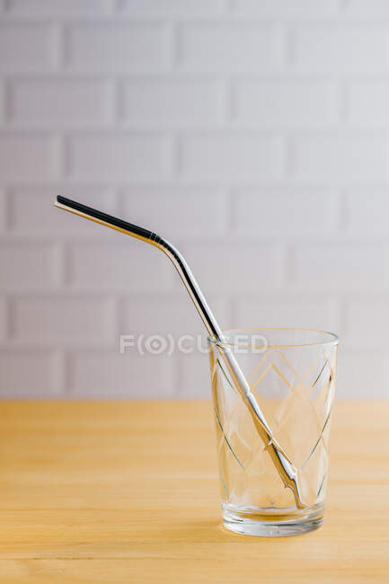Palha sustentável ecológica de aço brilhante em vidro vazio na mesa de madeira — Fotografia de Stock