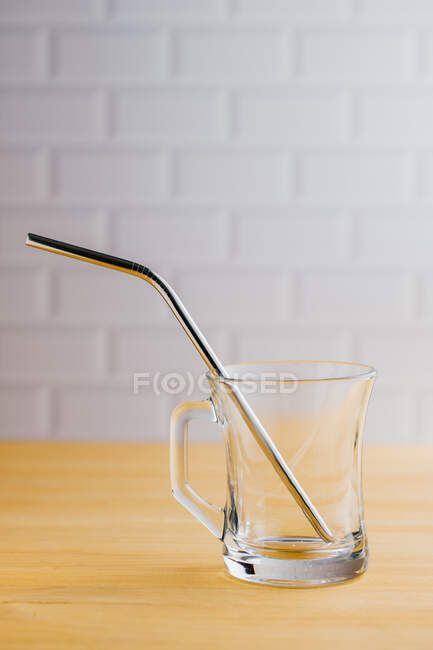 Palha sustentável ecológica de aço brilhante em vidro vazio na mesa de madeira — Fotografia de Stock