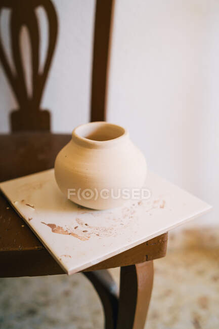 High angle of small light brown clay vase on square stand against blurred interior of light modern apartment — Stock Photo