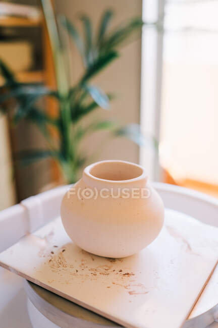 High angle of small light brown clay vase on square stand against blurred interior of light modern apartment — Stock Photo