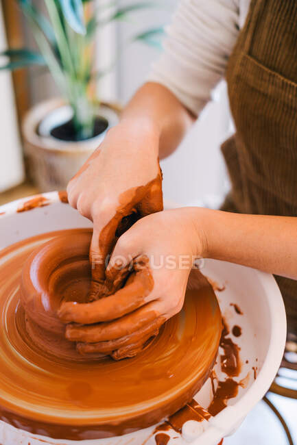 High angle of crop person in casual clothes making handmade pottery using special equipment while working in light contemporary studio — Stock Photo