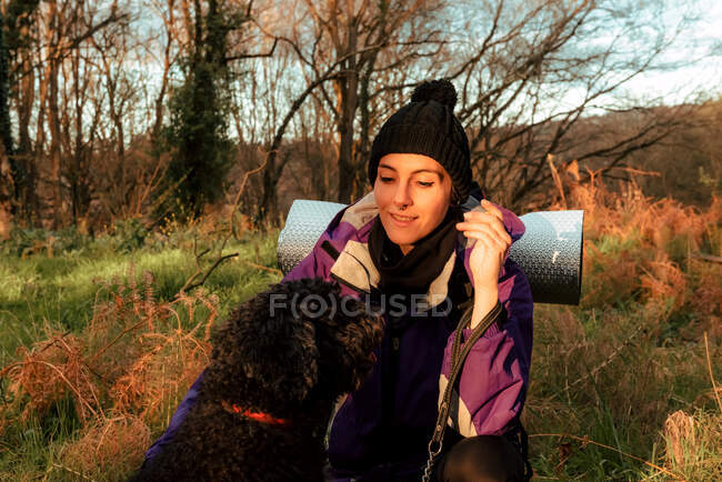 Cheerful young female hiker with dog in countryside — Stock Photo