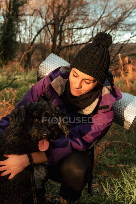 Joven excursionista alegre con perro en el campo - foto de stock