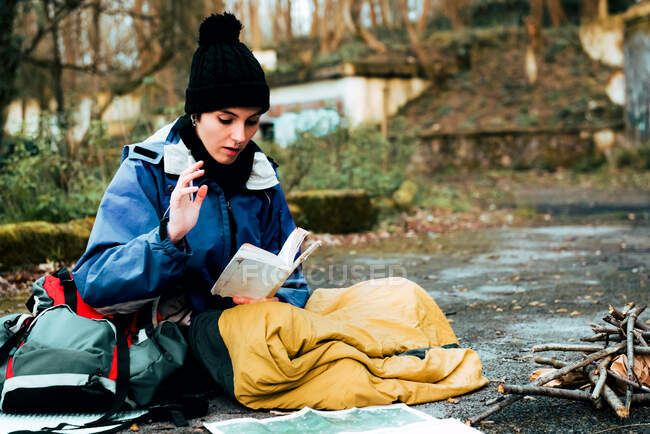 Young female backpacker making notes at campfire — Stock Photo