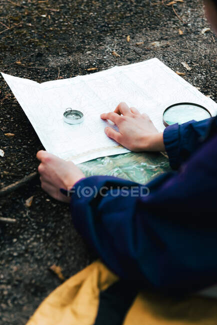 Caminhante irreconhecível navegando com mapa e bússola no campo — Fotografia de Stock