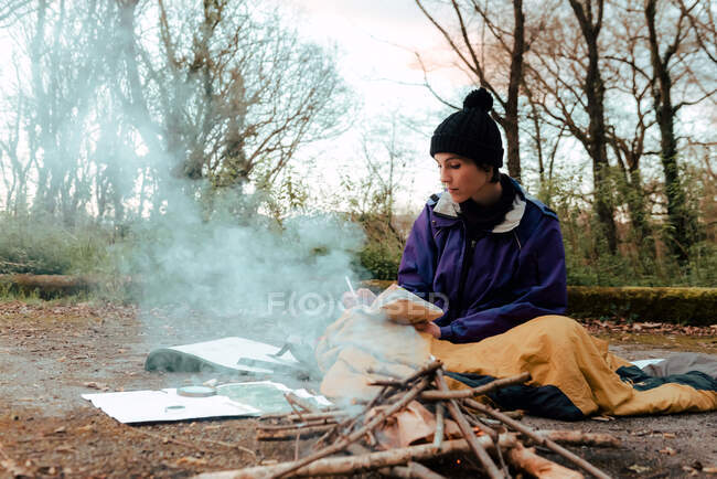 Jovem mochileiro feminino fazendo anotações na fogueira — Fotografia de Stock