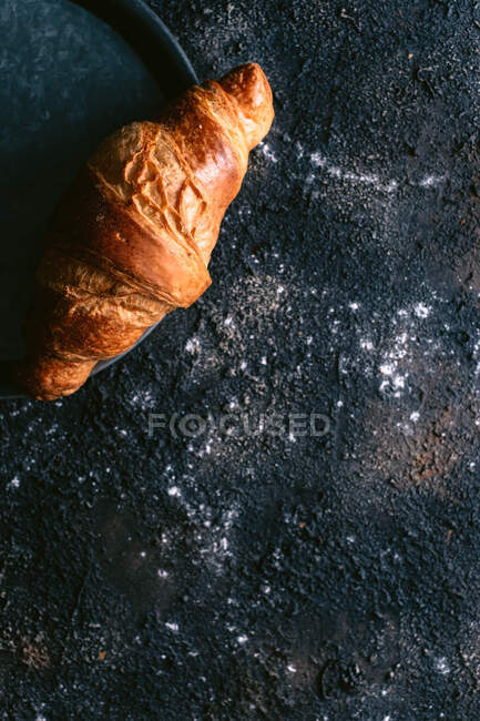 Vista superior do pão fresco macio colocado na bandeja de metal na mesa preta bagunçada durante o café da manhã — Fotografia de Stock