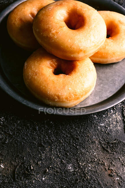 From above heap of yummy fresh doughnuts placed on metal plate on shabby black table — Stock Photo