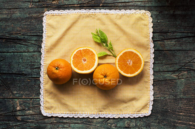 Mitades de naranjas frescas sobre una mesa rústica oscura de madera sobre un fondo oscuro - foto de stock
