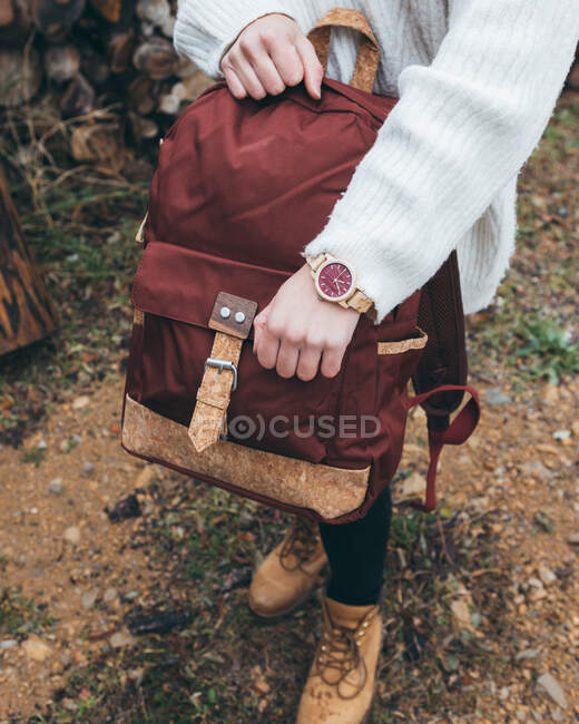 From above crop female hiker in casual outfit with trendy wristwatch holding stylish backpack while standing on trail in autumn day — Stock Photo