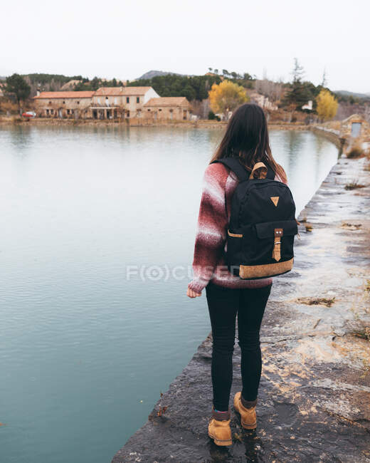 Young woman with backpack standing near lake — Stock Photo