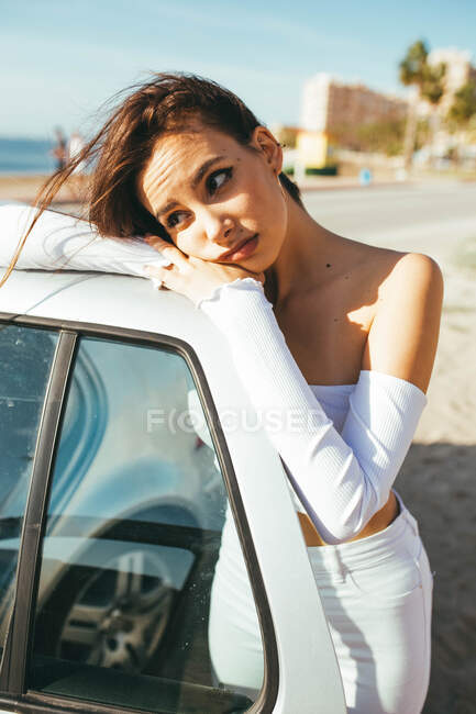 Набридла молода чутлива чарівна жінка в повсякденному одязі, дивлячись далеко, стоячи нахилившись поза дверима автомобіля — стокове фото