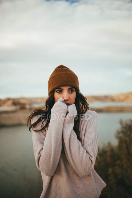 Jovem encantadora turista feminina olhando para longe enquanto desfruta de viagem de fim de semana para o lago no outono — Fotografia de Stock
