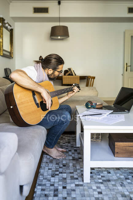 Стильний гітарист на дивані у вітальні — стокове фото