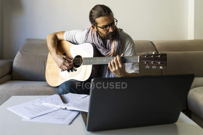 Stilvoller Gitarrist auf Couch im Wohnzimmer — Stockfoto