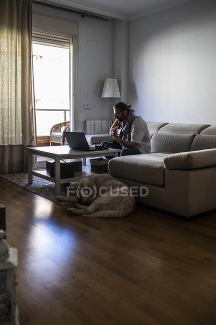 Стильный гитарист на диване в гостиной — стоковое фото