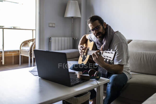 Стильний гітарист на дивані у вітальні — стокове фото