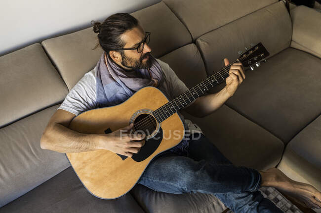 Guitariste élégant sur canapé dans le salon — Photo de stock