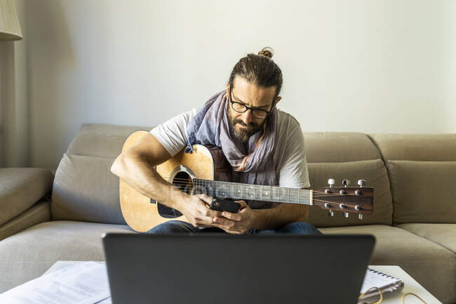 Jovem músico masculino navegando smartphone na sala de estar — Fotografia de Stock