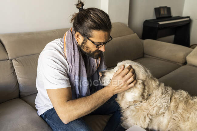 Satisfied guy petting Retriever at home — Stock Photo