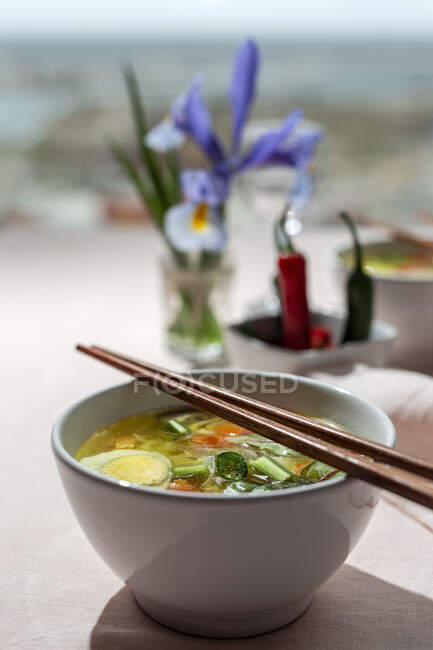 С восточного рамена здоровый суп с лапшой шиитаке, шпинатом, морковью, яйцами и чили на столе ресторана — стоковое фото
