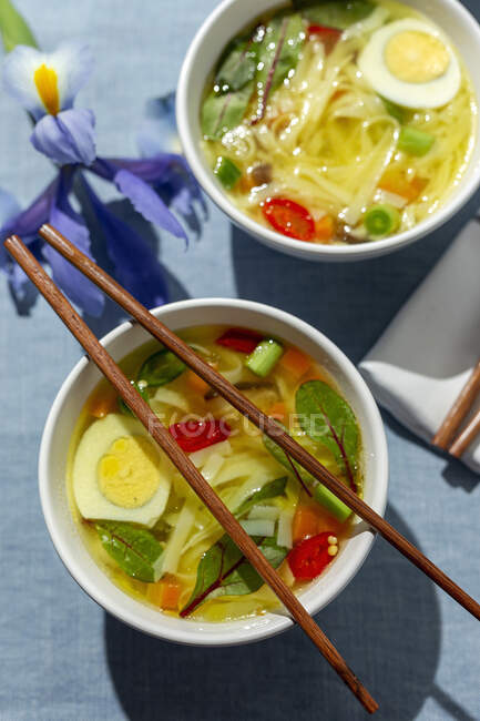 Sopa de fideos saludables de ramen oriental con shiitake, espinacas, zanahorias, huevos y chiles en la mesa del restaurante - foto de stock