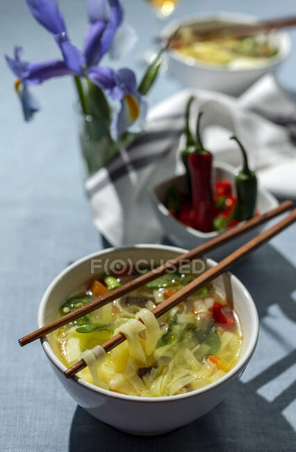 С восточного рамена здоровый суп с лапшой шиитаке, шпинатом, морковью, яйцами и чили на столе ресторана — стоковое фото
