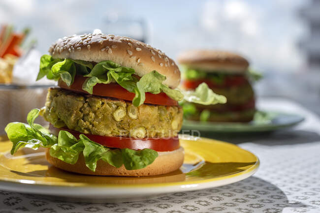 Hamburguesa de lenteja verde vegana sana casera con tomate, lechuga y papas fritas - foto de stock