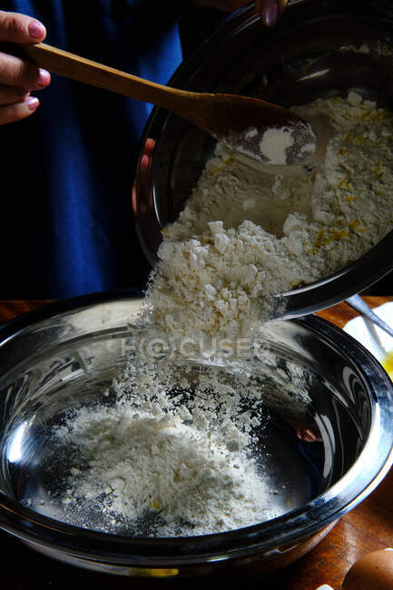 Unrecognizable female spilling wheat flour into metal bowl while preparing pastry at home — Stock Photo