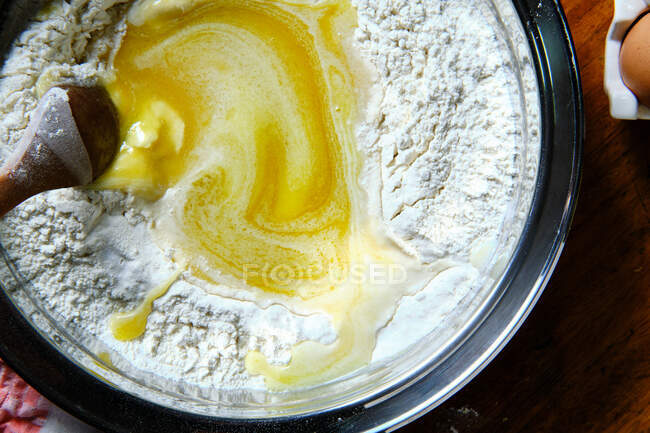Wooden spoon to mix soft pastry dough in metal bowl on table in kitchen — Stock Photo