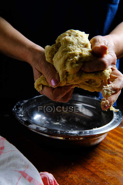 Anonymous female kneading fresh dough over table with lemon and napkin during pastry preparation at home — Stock Photo