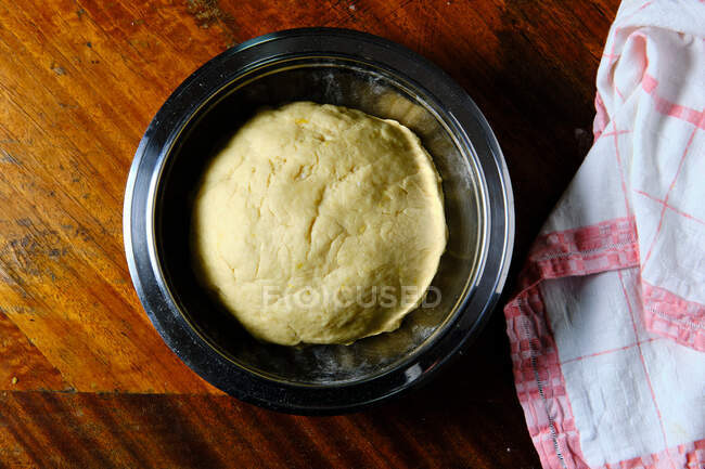 Top view of metal dough with fresh pastry dough placed on wooden table near cloth napkin in kitchen — Stock Photo