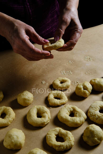 Анонімна жінка робить кільця з м'якого тіста під час приготування пончиків на столі на кухні — стокове фото