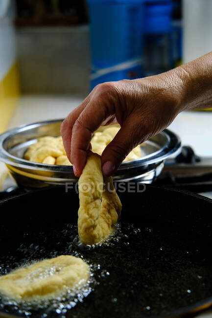 Dall'alto mani di persona irriconoscibili con mazzo di deliziose ciambelle che friggono in olio bollente caldo su stufa in cucina — Foto stock
