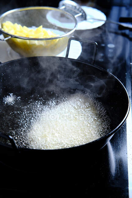 From above of boiling oil with white bubbles and steam in big black metal pan in modern kitchen — Stock Photo