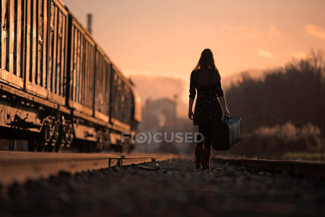 Mulher caminhando com uma mala pelos trilhos do trem — Fotografia de Stock