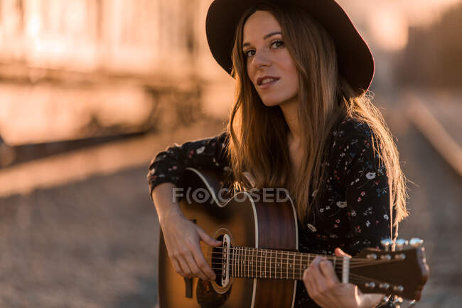 Frau spielt Gitarre auf Schienen — Stockfoto
