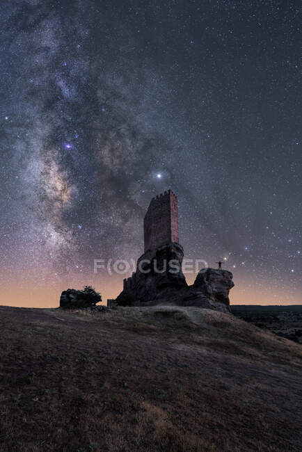 Silhouette back view of faceless traveler sightseeing remains of ancient castle under Milky Way at starry night — Stock Photo
