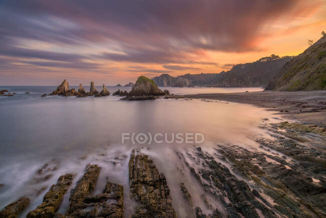 Potente ruscello d'acqua tra terreni rocciosi con cielo nuvoloso colorato brillante sullo sfondo — Foto stock