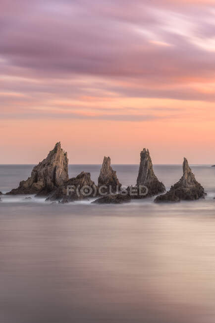 Dall'alto pittoresco scenario di rocce grezze tra il mare blu calmo sotto il cielo colorato della sera con raggi di sole che sfondano le nuvole durante il crepuscolo Costa Brava, Spagna — Foto stock
